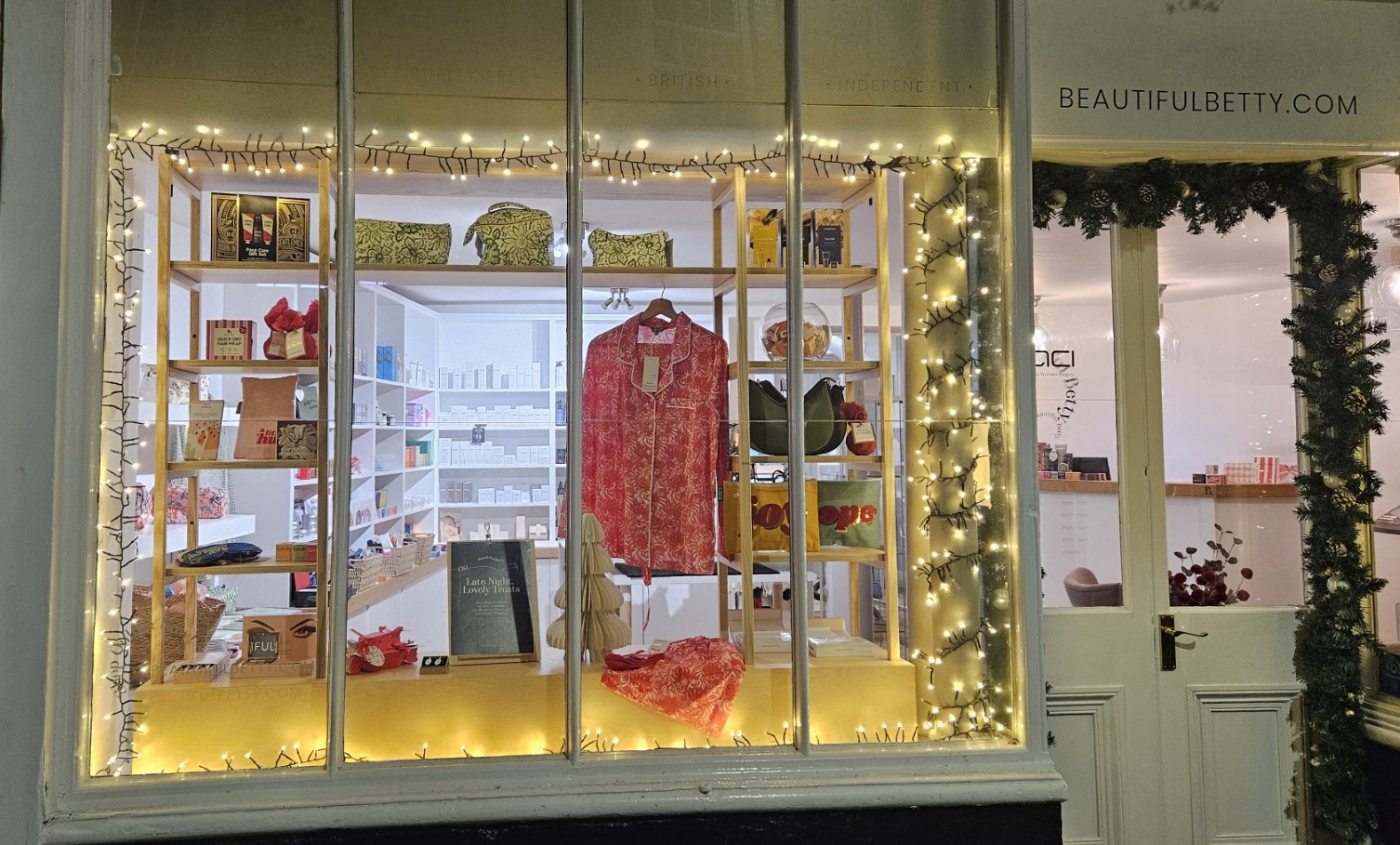 Hexham Christmas windows trail. The window for Beautiful Betty lit up at night and full of gifts including a pair of red pyjamas